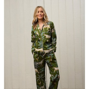 Könnte beinhalten: Grünes Pyjama-Set mit Dschungel-Tierdruck. Das langärmlige Oberteil hat eine Knopfleiste vorne und eine Brusttasche. Die Hose ist gerade geschnitten. Weiße Paspeln akzentuieren Kragen, Manschetten und Tasche.