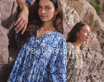 Può includere: Un abito a maniche lunghe con motivo floreale blu e bianco, scollo a V e vita arricciata. Il testo @BohoRobes è visibile al centro dell'abito. Il tessuto presenta una silhouette ampia e fluida con maniche voluminose.