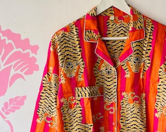 May include: A long-sleeved button-up shirt with a pink and orange striped pattern and a tiger print.