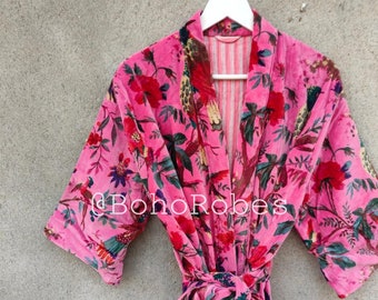 May include: Pink velvet robe with a floral print featuring birds and flowers. The robe has a tie belt and a contrasting striped lining.