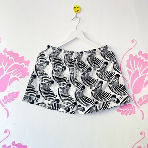 May include: White swim trunks with a black and white zebra print.