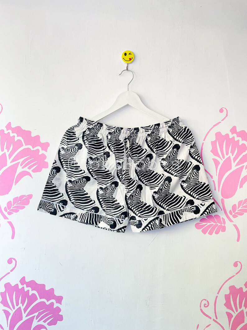 May include: White swim trunks with a black and white zebra print.