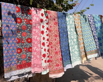 May include: A collection of eight colorful cotton fabric panels with floral and geometric patterns. The panels are hanging on a clothesline.