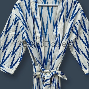 May include: A white cotton robe with a blue ikat pattern. The robe has a tie belt and long sleeves.