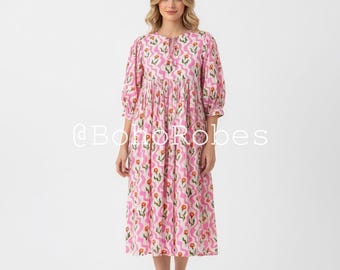 May include: A pink midi dress with a floral pattern. The dress has three-quarter sleeves and a gathered waist. The floral pattern includes orange and red flowers. The text "@BohoRobes" is visible on the dress.