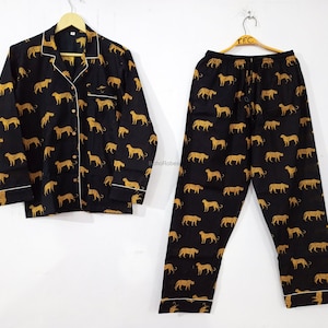 Pode incluir: Conjunto de pijama preto e dourado com padrão de leopardo. O conjunto inclui uma camisa de manga comprida com colarinho de botões e calças combinando.