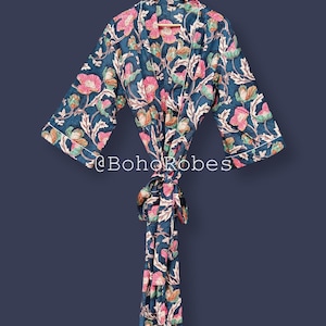 Può includere: Accappatoio blu scuro a fantasia floreale con fiori rosa e arancioni e foglie verdi. L'accappatoio ha un bordo bianco e una cintura abbinata. Il testo "@BohoRobes" è visibile.