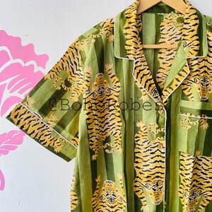 Puede incluir: Camisa de rayas verdes y amarillas con ribete blanco. La camisa tiene un estampado de tigres.