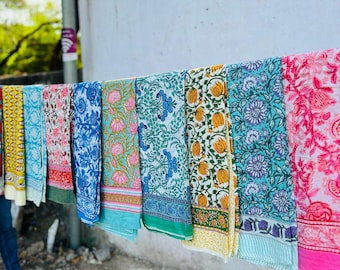 May include: A row of colorful printed fabric panels hanging on a clothesline. The panels feature floral and geometric patterns in shades of blue, pink, yellow, and green. The text "THE FABRIC CRAFT" is visible on a white wall behind the panels.