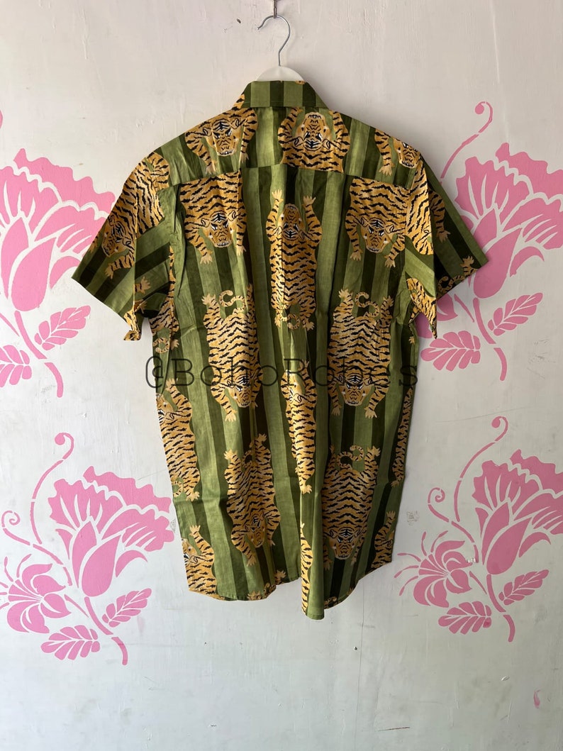May include: A green and gold short-sleeved button-down shirt with a tiger print.