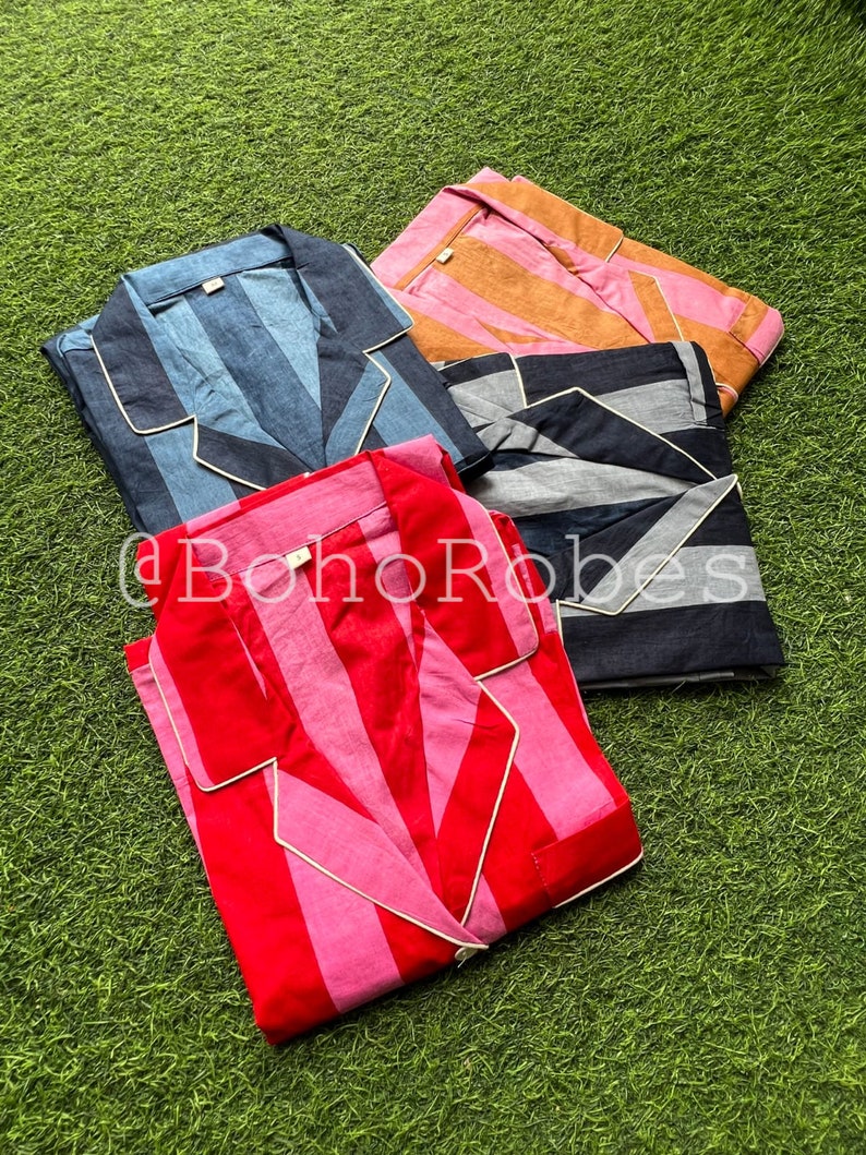 K&ouml;nnte beinhalten: Vier gestreifte Pyjamas in verschiedenen Farben: rosa und rot, blau und wei&szlig;, schwarz und wei&szlig; sowie orange und wei&szlig;. Die Pyjamas haben einen Knopfkrag und lange &Auml;rmel.