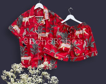 May include: Red pajama set with a tropical print featuring leopards, toucans, and palm trees. The set includes a short-sleeved shirt and matching shorts.