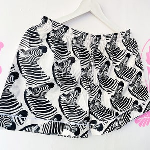 May include: White cotton shorts with a black and white zebra print.