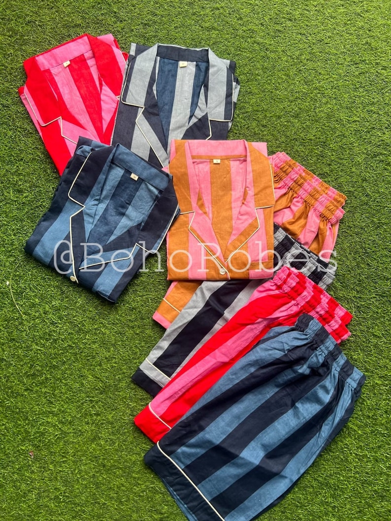K&ouml;nnte beinhalten: Ein Set gestreifter Pyjamas in verschiedenen Farben, darunter Pink, Blau, Orange und Schwarz. Die Pyjamas sind aus weicher Baumwolle gefertigt und perfekt zum Entspannen zu Hause.