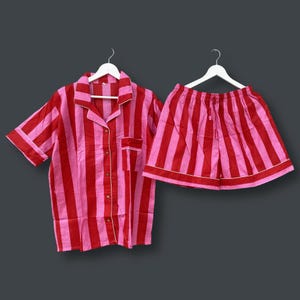 May include: A pink and red striped pajama set with a short-sleeved button-up shirt and matching shorts.