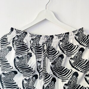 May include: White and black zebra print shorts with an elastic waistband and drawstring.