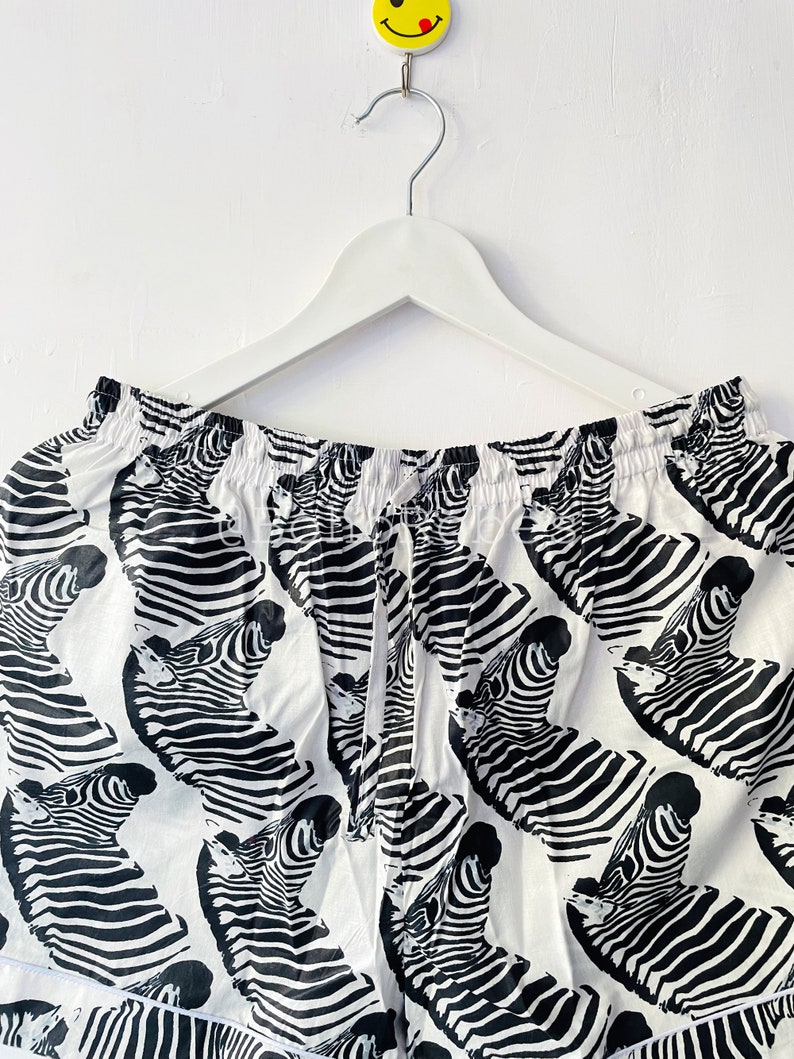 May include: White and black zebra print shorts with an elastic waistband and drawstring.