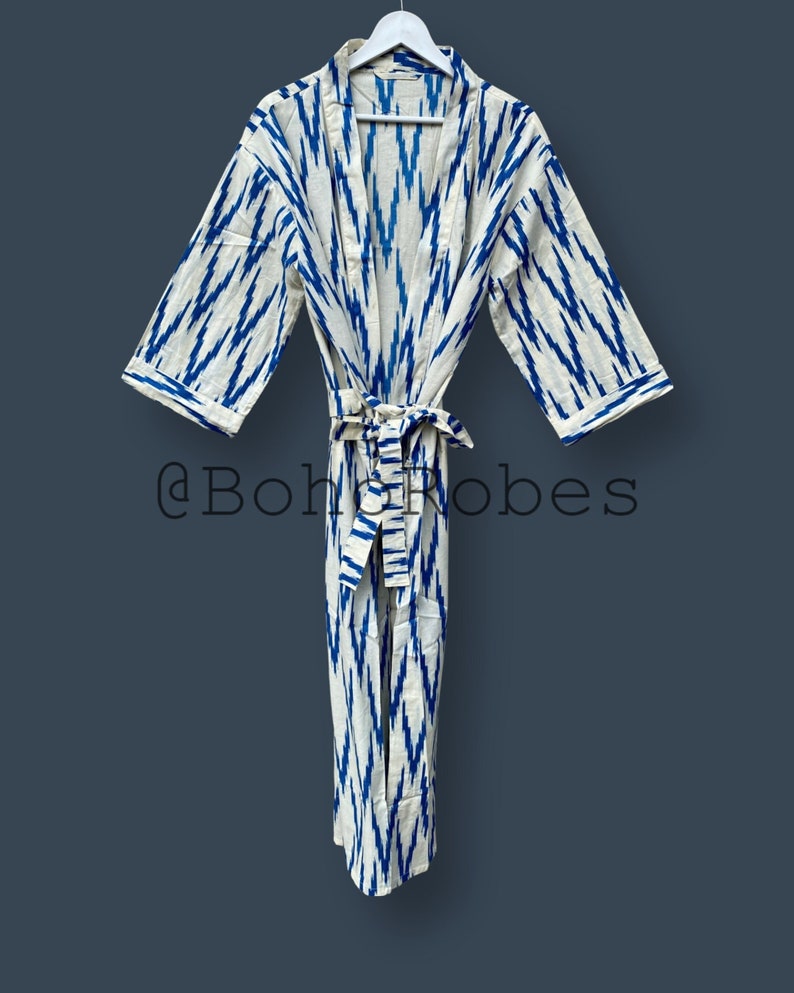 May include: A white and blue patterned robe with a long sleeve and a tie belt. The robe has a blue and white ikat pattern.