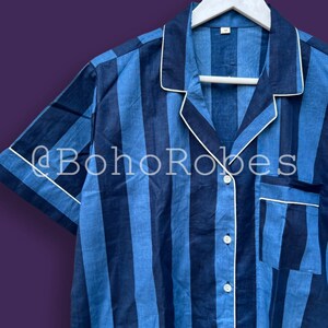 K&ouml;nnte beinhalten: Ein kurz&auml;rmeliges Hemd mit blau-wei&szlig;em Streifenmuster, wei&szlig;em Kragen und Knopfleiste. Das Hemd hat einen wei&szlig;en Besatz am Kragen und an den Manschetten.