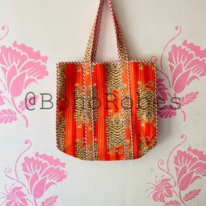 May include: Orange and white tote bag with a tiger print. The bag has a white and red striped trim.