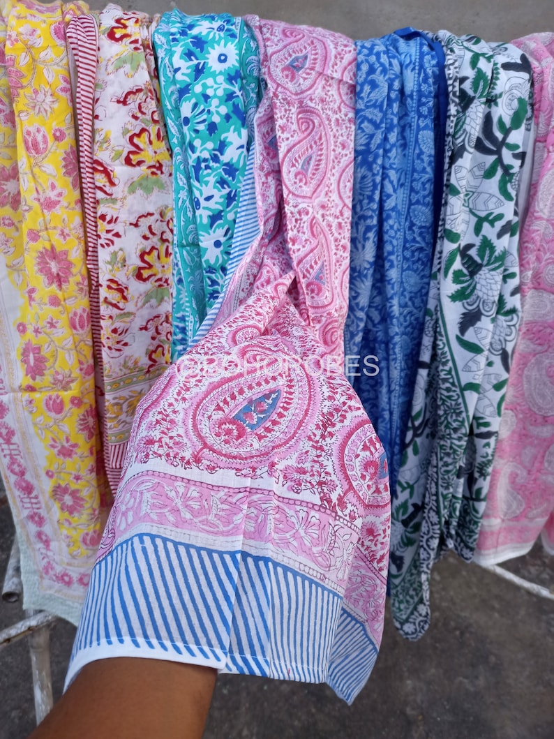 May include: A collection of colourful cotton fabric strips with various floral and paisley patterns. The fabric is white with pink, blue, green, and yellow accents.