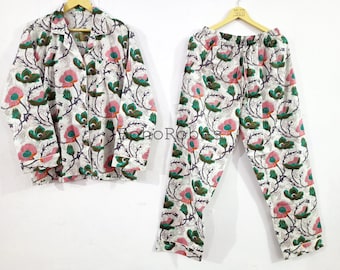 May include: A white pajama set with a floral print featuring pink, green, and brown colors. The set includes a long-sleeved shirt with a button-up closure and matching pants.