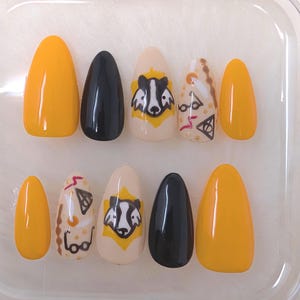 Può includere: Set di dieci unghie finte a tema Harry Potter. Le unghie sono di vari colori, tra cui giallo, nero e beige. Alcune unghie presentano un design di tasso, mentre altre hanno uno stemma di casa di Hogwarts o altre immagini legate a Harry Potter.