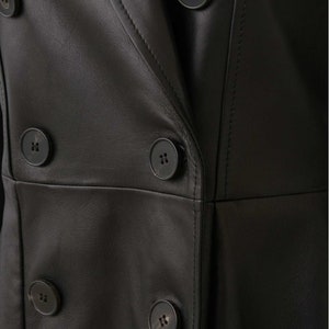 May include: Close-up of a black leather jacket with a double-breasted closure and four large buttons.