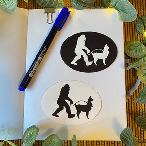 May include: Two oval stickers with a black and white silhouette of a Bigfoot walking a llama. The sticker on the left has a black background and white silhouette. The sticker on the right has a white background and black silhouette.