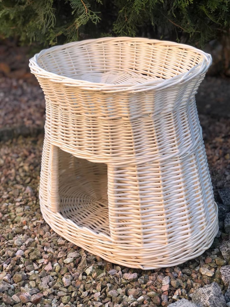 Peut inclure: Lit pour chat en osier blanc avec une ouverture ronde sur le c&ocirc;t&eacute;. Le lit est de forme ovale et poss&egrave;de un bord sur&eacute;lev&eacute;.