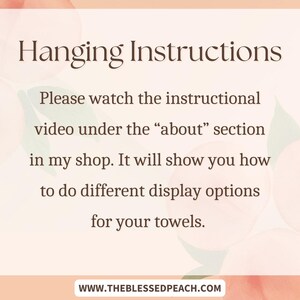 May include: A peach-colored graphic with the text "Hanging Instructions." The text advises viewers to watch an instructional video in the shop's "about" section for towel display options. The website address is also included.