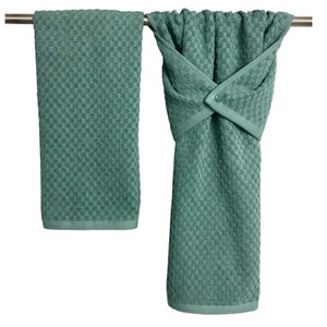 May include: Two green kitchen towels hanging on a silver bar. One towel is folded and the other is hanging down with a button closure.