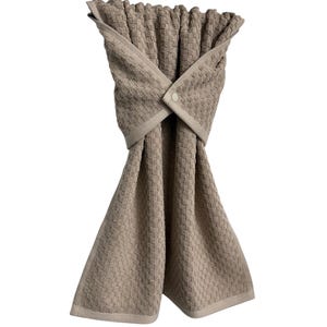 May include: A beige kitchen towel with a woven pattern. The towel is folded and secured with a button closure. The towel has a light beige border and is designed for hanging.