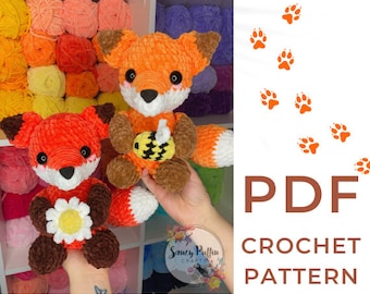May include: Crochet pattern PDF for making two plush fox toys. One fox holds a bee and the other holds a daisy. The pattern is available for download.
