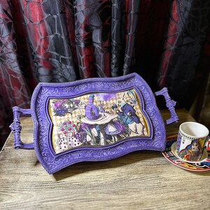 May include: Purple serving tray with an ornate frame and a whimsical Alice in Wonderland themed design. The tray has two handles on the sides.