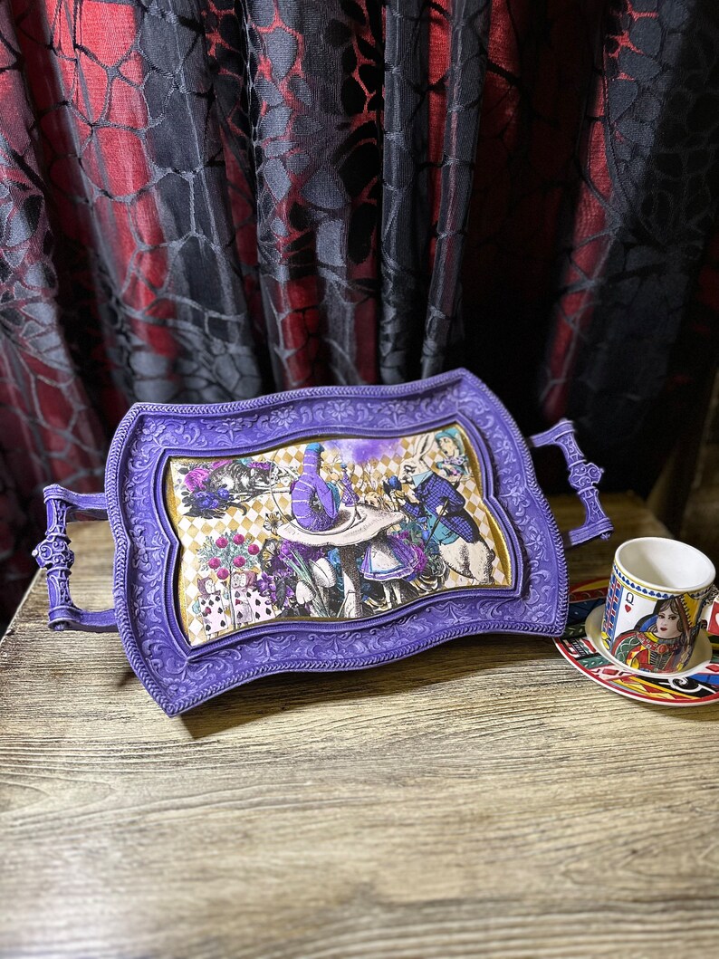 May include: Purple serving tray with an ornate frame and a whimsical Alice in Wonderland themed design. The tray has two handles on the sides.