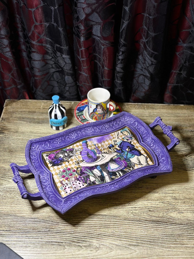 May include: Purple serving tray with a whimsical Alice in Wonderland design featuring the Mad Hatter, the White Rabbit, and Alice. The tray has two handles and a decorative border.