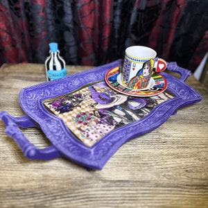 May include: Purple serving tray with ornate detailing and a whimsical Alice in Wonderland design. The tray features a teacup and saucer with a Queen of Hearts design.
