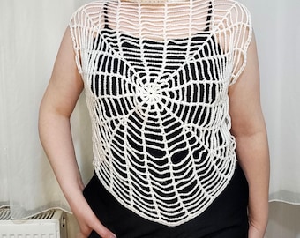 May include: White crochet top with a spiderweb design. The top is sleeveless and has a loose fit.