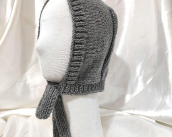 May include: A grey knitted bonnet with a long tie. The bonnet has a sparkly texture.