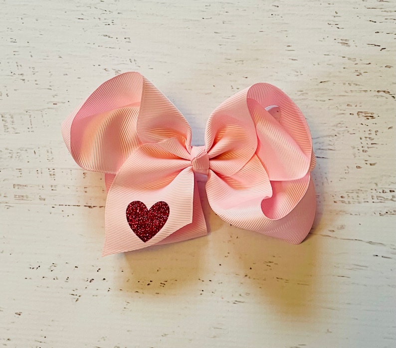 May include: A pink hair bow with a red glitter heart in the center.