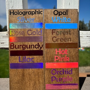 May include: Two wooden signs with different holographic and opal finishes. The left sign has the text "Holographic" and lists the colors "Silver", "Rose Gold", "Burgundy", and "Lilac". The right sign has the text "Opal" and lists the colors "White", "Forest Green", "Hot Pink", and "Orchid Purple".