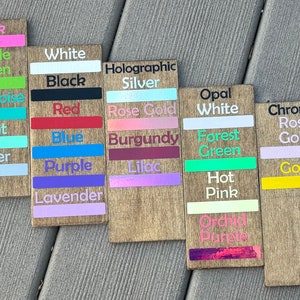 May include: Wooden signs with color swatches and names, including Pink, Apple Green, White, Black, Holographic Silver, Rose Gold, Burgundy, Lilac, Opal White, Forest Green, Hot Pink, Orchid Purple, Chrome Rose Gold, and Gold.