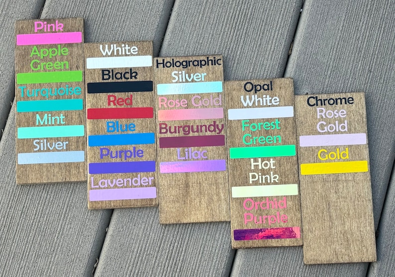 May include: Wooden signs with color swatches and names, including Pink, Apple Green, White, Black, Holographic Silver, Rose Gold, Burgundy, Lilac, Opal White, Forest Green, Hot Pink, Orchid Purple, Chrome Rose Gold, and Gold.
