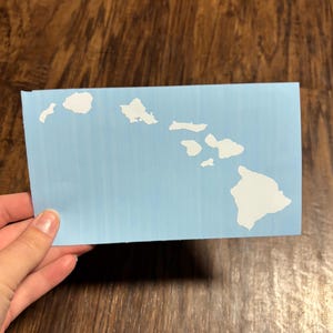 May include: A blue stencil of the Hawaiian islands, cut out in white, on a light blue background.