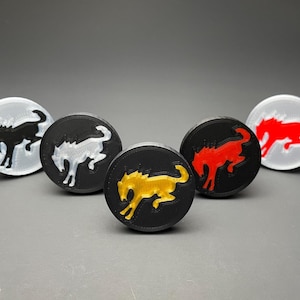 May include: Five circular emblems featuring a raised horse silhouette in the center. The set includes a clear disc with a black horse, a black disc with a white horse, a black disc with a gold horse, a black disc with a red horse, and a white disc with a red horse.