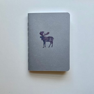 May include: A gray notebook with a purple moose silhouette on the front cover.