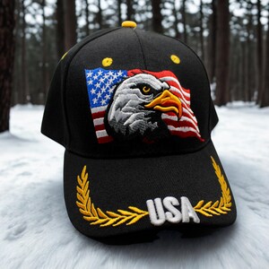 Może przedstawiać: Czarna czapka bejsbolowa z haftowaną amerykańską flagą i wzorem orła bielika. Czapka ma napis "USA" w kolorze białym, obramowany złotym wieńcem laurowym. Czapka ma ż&oacute;łty guzik.