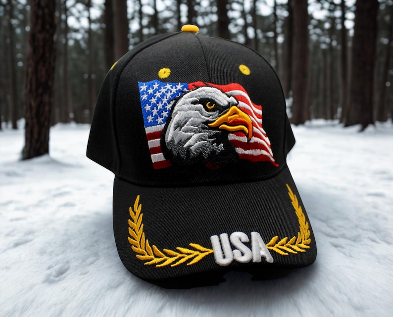 Może przedstawiać: Czarna czapka bejsbolowa z haftowaną amerykańską flagą i wzorem orła bielika. Czapka ma napis "USA" w kolorze białym, obramowany złotym wieńcem laurowym. Czapka ma ż&oacute;łty guzik.