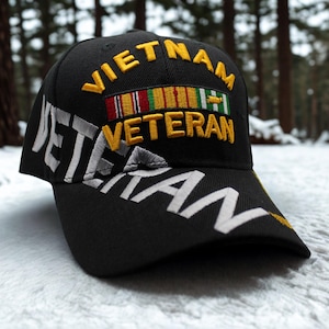 Könnte beinhalten: Eine schwarze Baseballkappe mit dem gestickten gelben Text VIETNAM VETERAN auf der Vorderseite. Über dem Wort VETERAN befindet sich eine bunte, gestickte Ordensspange. Das Wort VETERAN ist zudem in großen weißen Buchstaben auf den Schirm gestickt.